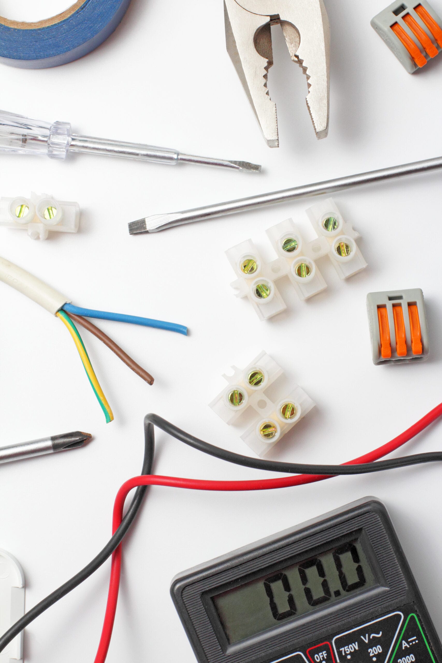 Flat lay, appliances and electrician tools on a rustic white background, close-up, vertical frame.